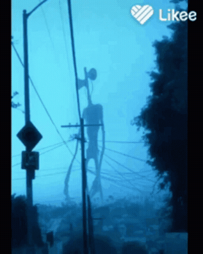 A Siren Head Is Silhouetted Against A Blue Sky Behind Telephone Poles GIF