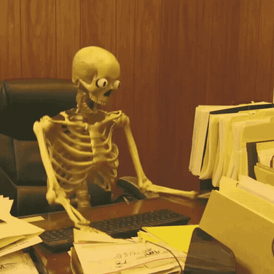 A Skeleton Is Sitting At A Desk With A Bunch Of Papers Including One That Says ' A ' On It GIF