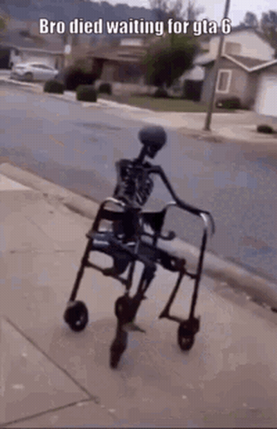A Skeleton Is Sitting In A Wheelchair On The Sidewalk . GIF