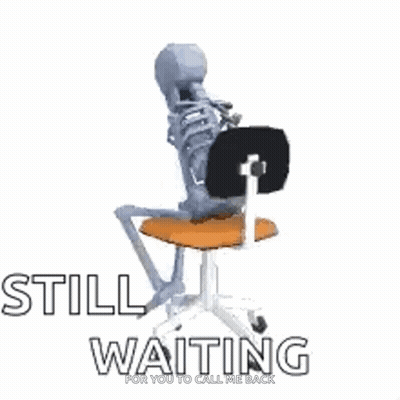 A Skeleton Is Sitting On A Chair With The Words `` Still Waiting '' Written On It . GIF