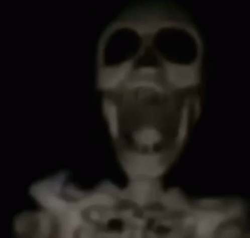 A Skeleton Is Standing In The Dark With A Stick In Its Mouth . GIF