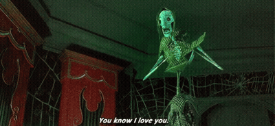 A Skeleton With A Green Mask Is Saying `` You Know I Love You '' In A Dark Room . GIF
