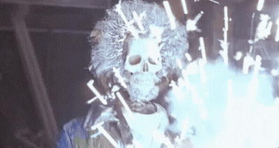 A Skeleton With A Wig And A Skull On His Head Is Surrounded By Sparklers . GIF