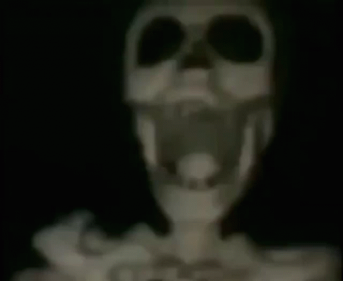 A Skeleton With Its Mouth Open Is Hanging From A Ceiling . GIF