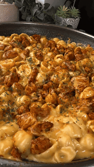 A Skillet Filled With Macaroni And Cheese With Chicken GIF