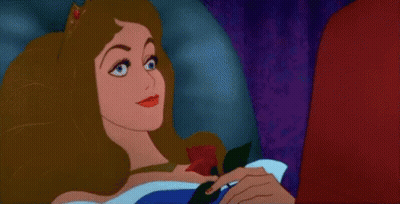 a sleeping beauty from sleeping beauty is holding a rose in her hand .