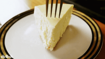 A Slice Of Cheesecake On A Plate With The Word Delish On The Bottom Right GIF