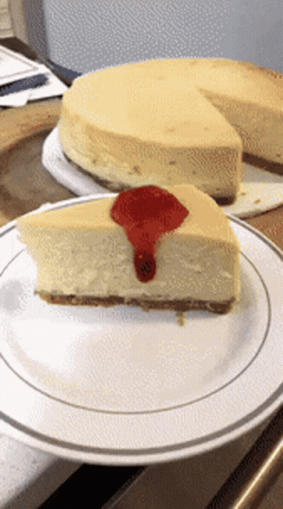 A Slice Of Cheesecake With A Strawberry Sauce On Top GIF