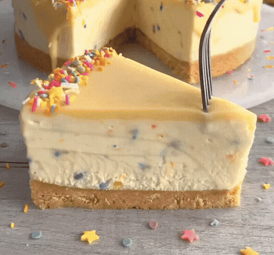 A Slice Of Cheesecake With Sprinkles On Top And A Fork Sticking Out Of It GIF