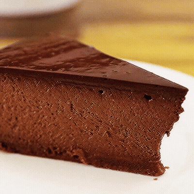 A Slice Of Chocolate Cheesecake Is On A White Plate GIF