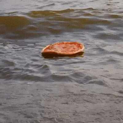 A Slice Of Pizza Is Floating In The Ocean GIF