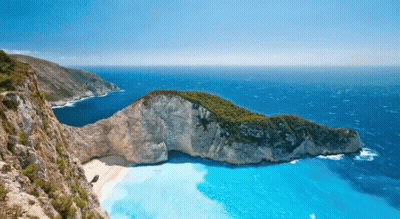 A Small Island In The Middle Of The Ocean With A Boat In The Water GIF