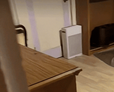 A Small White Box Is Sitting On The Floor Next To A Wooden Table GIF