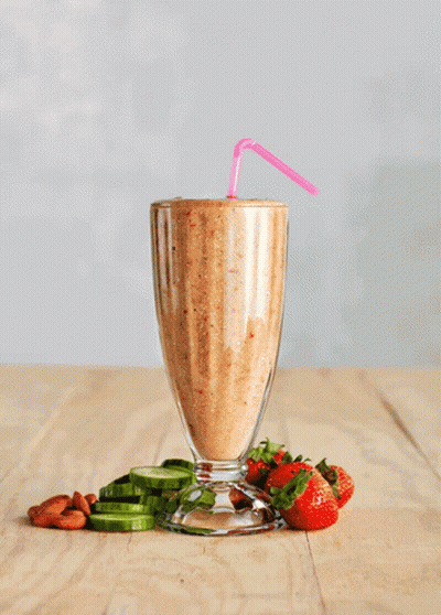 A Smoothie With Strawberries And Cucumbers On The Table GIF