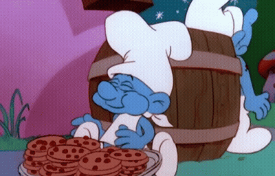 A Smurf In A Chef 'S Hat Is Holding A Bowl Of Chocolate Chip Cookies . GIF