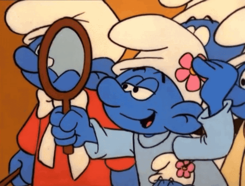 A Smurf With A Pink Flower On His Hat Looks At Himself In A Mirror GIF
