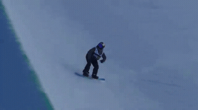 A Snowboarder Is Doing A Trick In The Air While Riding Down A Snowy Hill . GIF