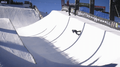 A Snowboarder Is Doing A Trick On A Snowy Ramp With A Breck Banner In The Background GIF