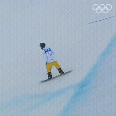 A Snowboarder Is Doing A Trick On A Snowy Slope With The Olympic Rings In The Background GIF
