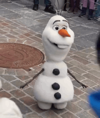 A Snowman Is Standing On A Brick Sidewalk With A Manhole Cover In The Background GIF