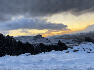 A Snowy Hillside With A Mountain In The Background GIF