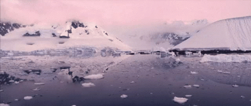 A Snowy Landscape With Mountains And Ice In The Water GIF