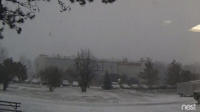 A Snowy Parking Lot In Front Of A Building With The Word Nest On The Bottom GIF
