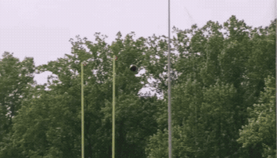 A Soccer Ball Is Flying Through The Air In Front Of A Forest GIF