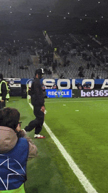 A Soccer Field With A Solo Recycle Sign In The Background GIF