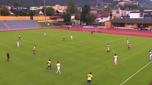 A Soccer Game Is Being Played On A Field With A Scoreboard That Says Dac 0-0 Om GIF