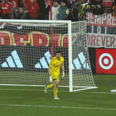a soccer goalie wearing a yellow adidas jersey runs towards the goal