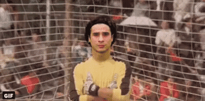 A Soccer Goalie With His Arms Crossed Is Standing In Front Of A Soccer Net . GIF