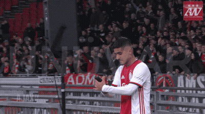 A Soccer Player Holds A Microphone In Front Of A Banner That Says Ajax Wallpaper GIF