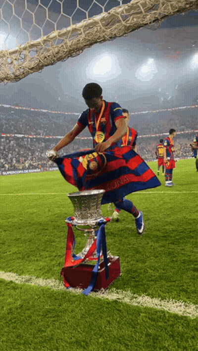 A Soccer Player Holds A Trophy And A Flag That Says Barcelona GIF