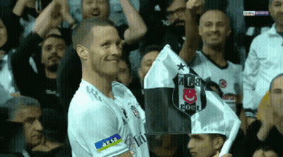 A Soccer Player Holds Up A Flag With A Shield On It GIF