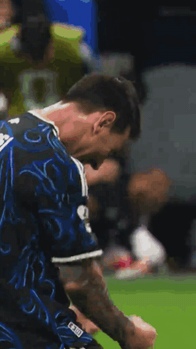 A Soccer Player In A Blue And Black Jersey Is Standing On A Field . GIF
