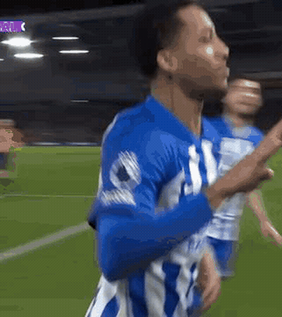 A Soccer Player In A Blue And White Uniform Is Celebrating A Goal On A Field . GIF