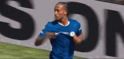 A Soccer Player In A Blue Shirt Is Running On A Field In Front Of A Large Sign . GIF