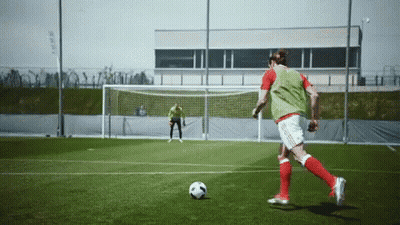 A Soccer Player In A Green Vest Kicks A Soccer Ball GIF