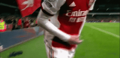 A Soccer Player In A Red Emirates Jersey Is Hugging Another Player On The Field . GIF