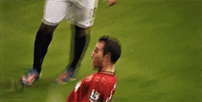 A Soccer Player In A Red Jersey Is Being Tackled By Another Player On A Field . GIF
