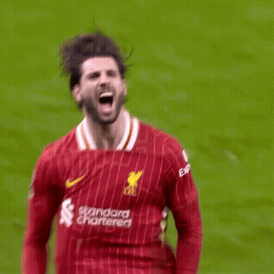 A Soccer Player In A Red Jersey Is Kicking A Ball On A Soccer Field . GIF