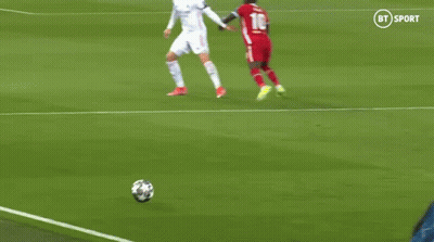 A Soccer Player In A Red Jersey Is Kicking A Soccer Ball While Another Player Tries To Stop Him . GIF