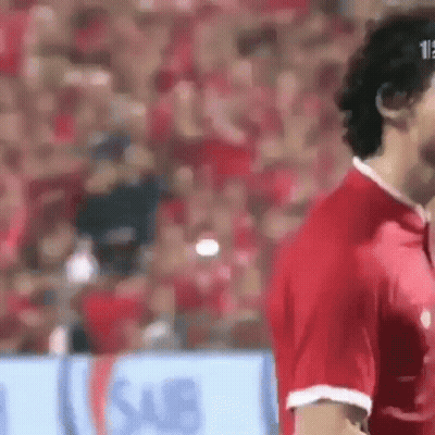 A Soccer Player In A Red Shirt Is Standing In Front Of A Crowd . GIF