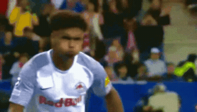 A Soccer Player In A White Red Bull Jersey Is Running On The Field . GIF