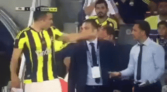 A Soccer Player In A Yellow And Black Striped Shirt Is Shaking Hands With A Man In A Suit GIF