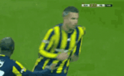 A Soccer Player In A Yellow And Blue Striped Jersey Is Being Tackled By Another Player GIF