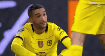 A Soccer Player In A Yellow Jersey Is Kneeling Down Next To Another Soccer Player . GIF