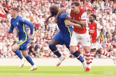 A Soccer Player Is Being Tackled By Another Player During A Game . GIF