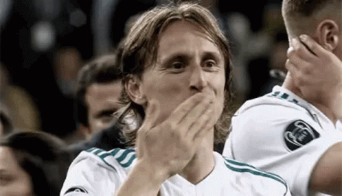 A Soccer Player Is Covering His Mouth With His Hands While Another Player Applauds . GIF